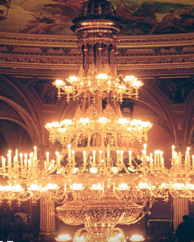 A chandelier lit up inside an opera house