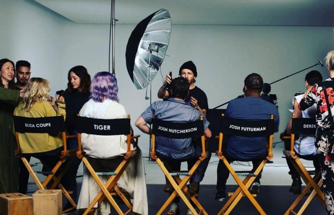 Cast in director's chairs on a studio set