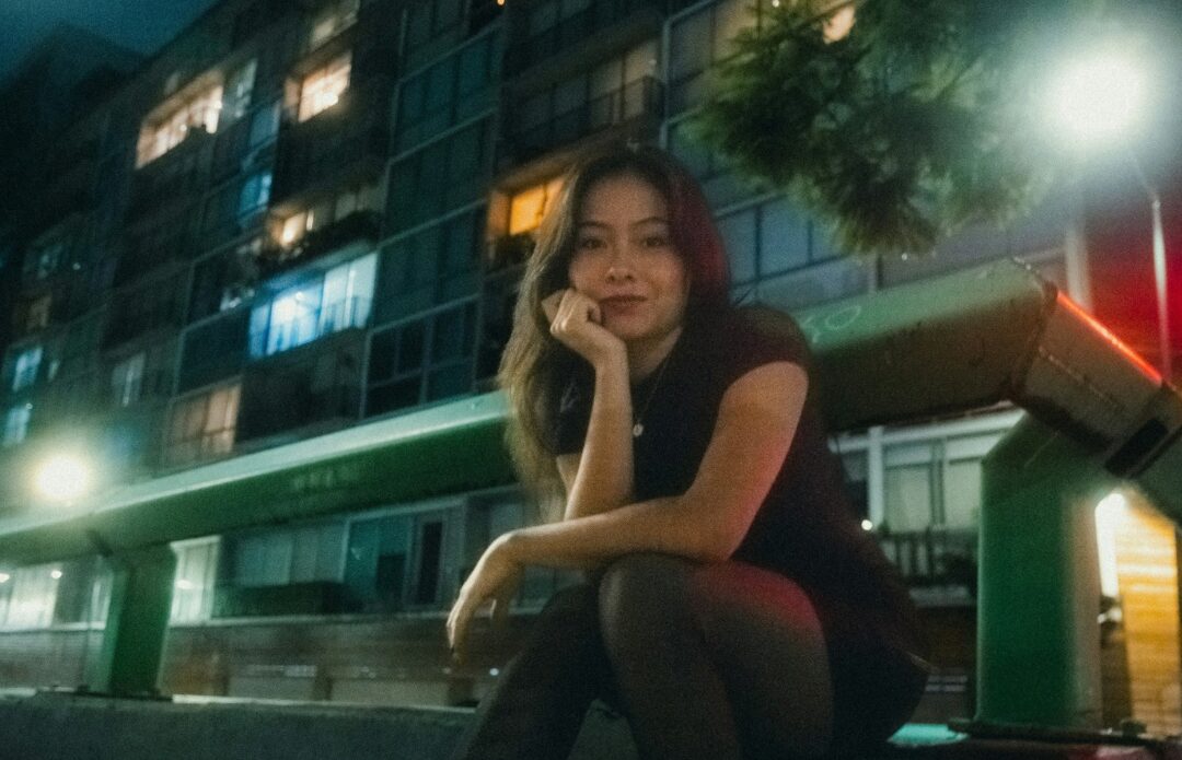 A creative sitting outside an apartment block at night